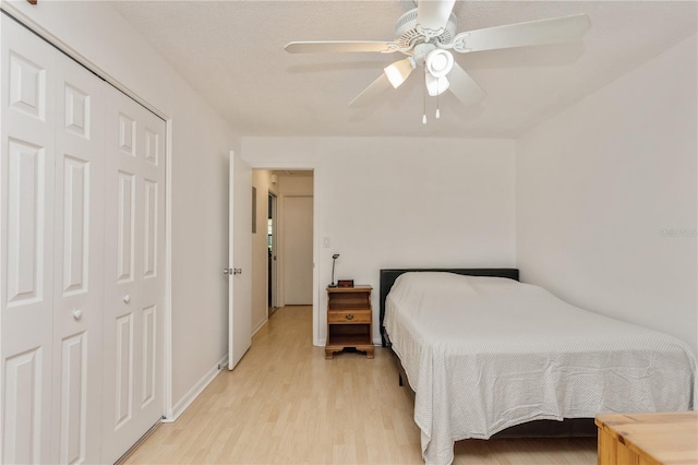 bedroom with light wood finished floors, baseboards, a ceiling fan, and a closet