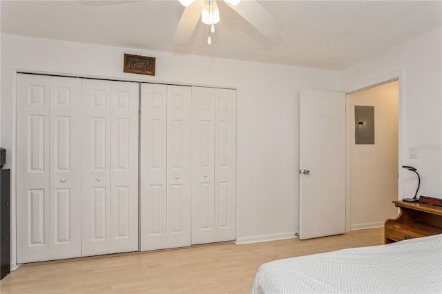 bedroom featuring ceiling fan, a closet, light wood-type flooring, and electric panel