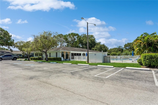 uncovered parking lot with a community pool and fence