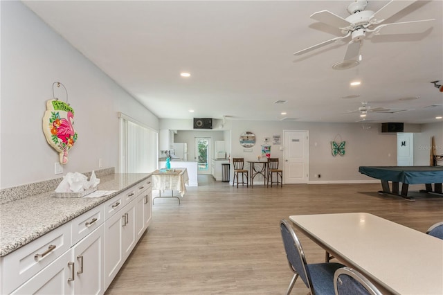 kitchen featuring recessed lighting, white cabinetry, baseboards, light stone countertops, and light wood finished floors