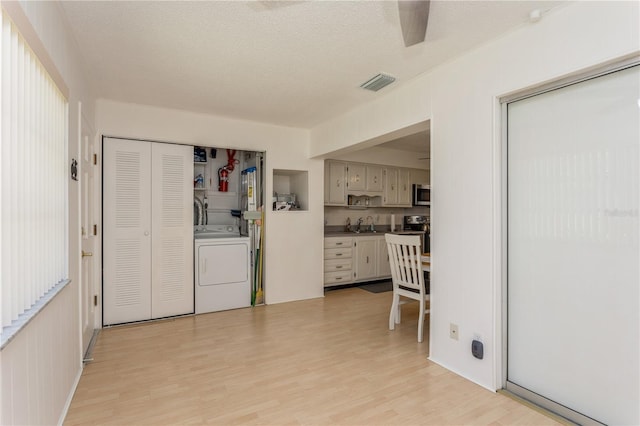 interior space with washer / dryer, light wood-style flooring, visible vents, and a textured ceiling