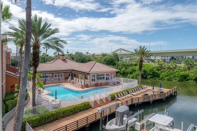 view of swimming pool featuring a boat dock, a patio area, and a water view