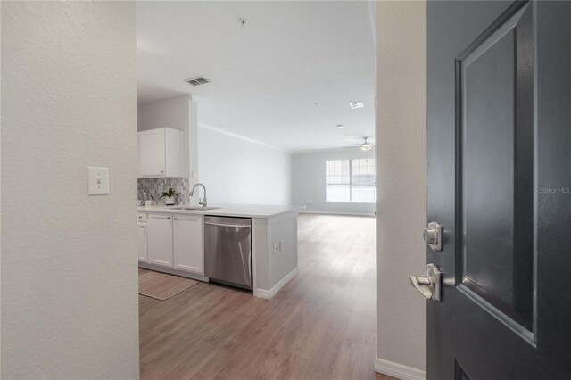 kitchen featuring decorative backsplash, dishwasher, white cabinets, and light hardwood / wood-style flooring