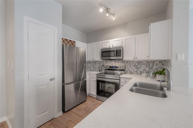 kitchen featuring white cabinets, sink, appliances with stainless steel finishes, tasteful backsplash, and light hardwood / wood-style floors