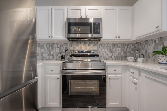 kitchen with backsplash, stainless steel appliances, and white cabinetry