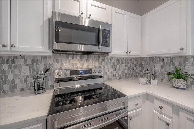 kitchen with backsplash, stainless steel appliances, white cabinetry, and light stone counters