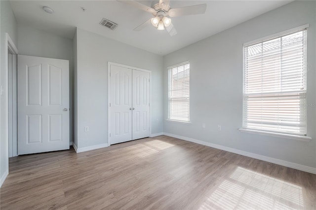 unfurnished bedroom featuring a closet, light hardwood / wood-style flooring, and ceiling fan