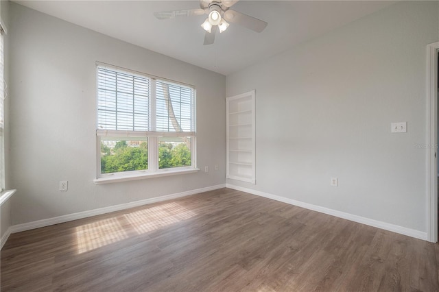 spare room featuring ceiling fan, built in features, and dark wood-type flooring