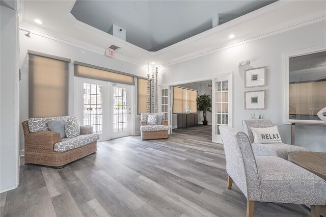 living area with french doors, a towering ceiling, and light hardwood / wood-style flooring