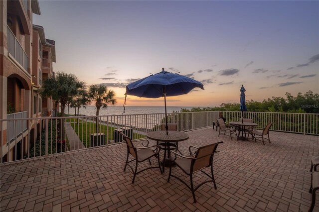 patio terrace at dusk featuring a water view