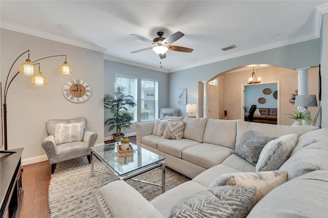 living room with ceiling fan with notable chandelier, hardwood / wood-style floors, ornamental molding, and decorative columns