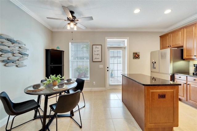 kitchen featuring ceiling fan, a kitchen island, crown molding, and stainless steel fridge