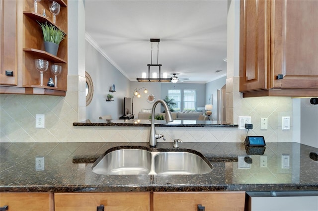 kitchen with ceiling fan, dark stone countertops, sink, hanging light fixtures, and ornamental molding