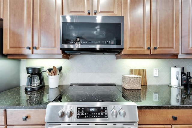 kitchen with decorative backsplash, appliances with stainless steel finishes, and dark stone countertops