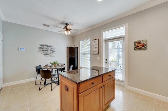 kitchen featuring a wealth of natural light, a kitchen island, dark stone counters, ceiling fan, and light tile patterned floors