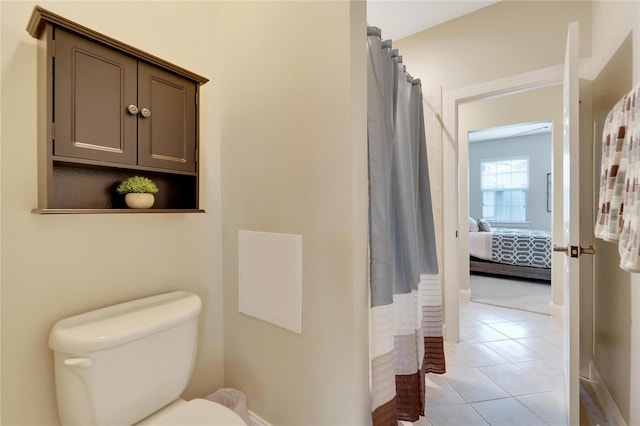 bathroom featuring toilet, a shower with shower curtain, and tile patterned flooring