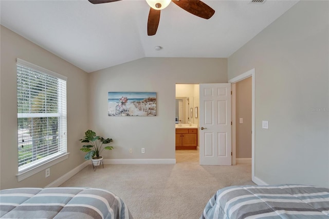 carpeted bedroom with vaulted ceiling, ceiling fan, ensuite bath, and multiple windows