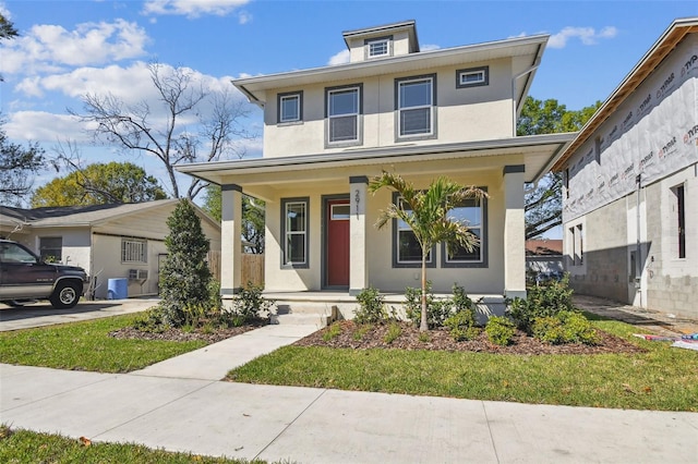 american foursquare style home featuring stucco siding and covered porch