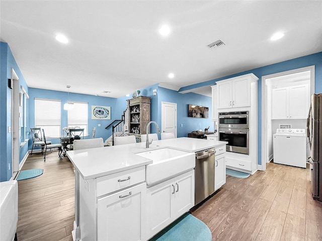 kitchen featuring appliances with stainless steel finishes, sink, pendant lighting, a center island with sink, and white cabinets