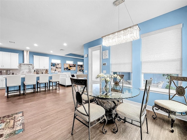 dining area with light wood-type flooring and an inviting chandelier