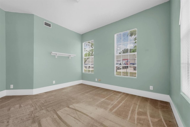 carpeted spare room with visible vents and baseboards