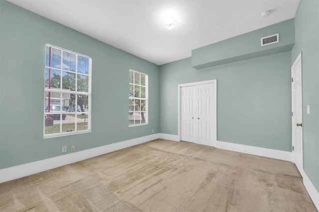 unfurnished room featuring light colored carpet, visible vents, and baseboards