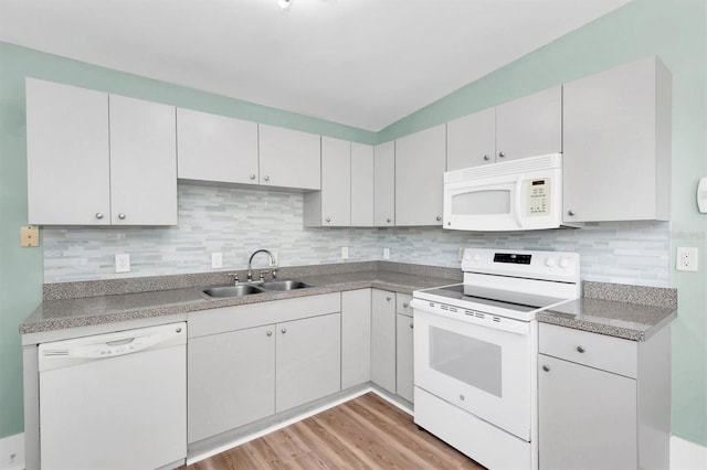 kitchen featuring white appliances, white cabinets, a sink, and decorative backsplash