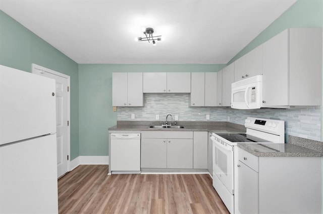 kitchen featuring white appliances, a sink, light wood-style floors, white cabinets, and decorative backsplash