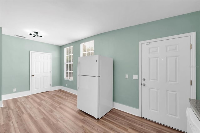 kitchen with light wood-style floors, freestanding refrigerator, visible vents, and baseboards