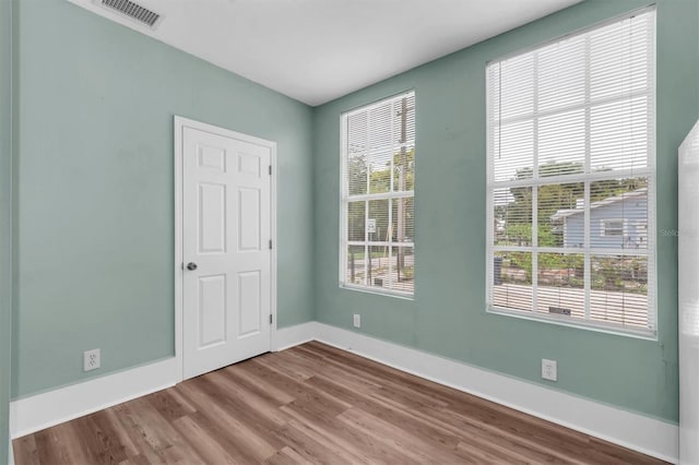 spare room with visible vents, baseboards, and wood finished floors