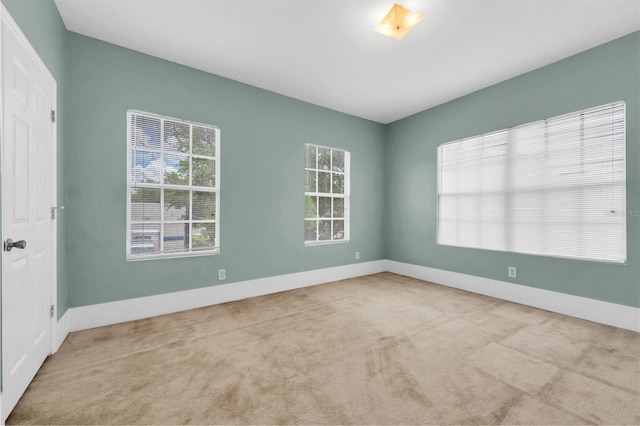 empty room featuring baseboards and light colored carpet