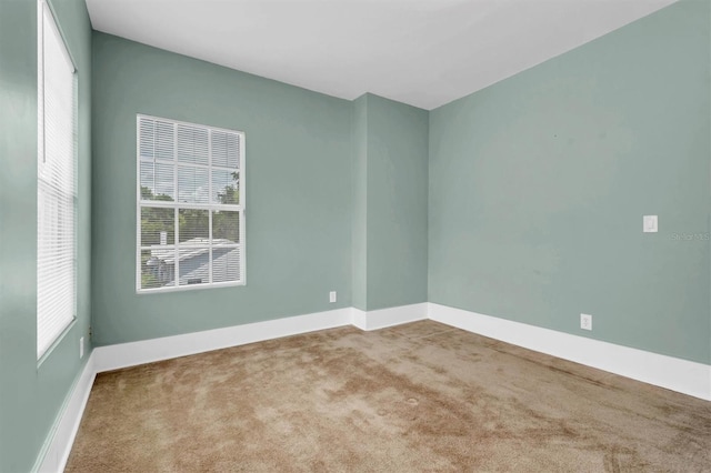 spare room featuring carpet floors and baseboards