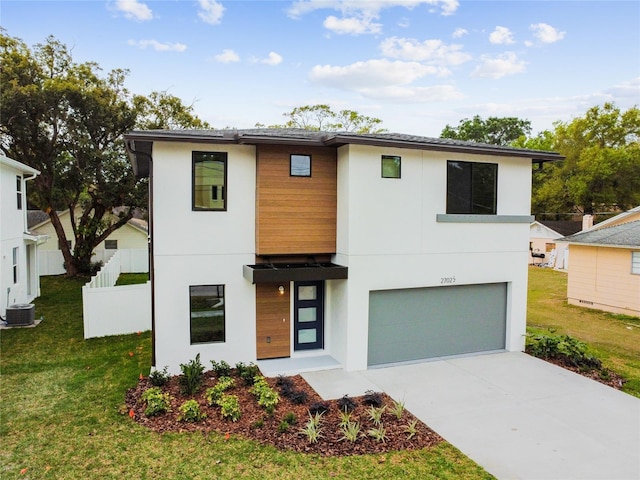 contemporary home with stucco siding, central air condition unit, concrete driveway, a front yard, and fence