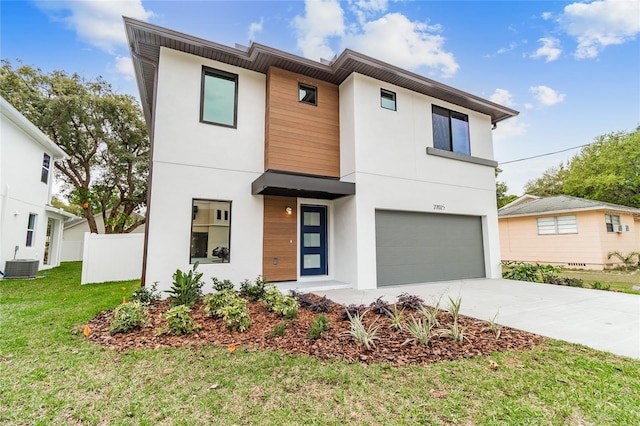 modern home with concrete driveway, an attached garage, a front yard, central AC, and fence