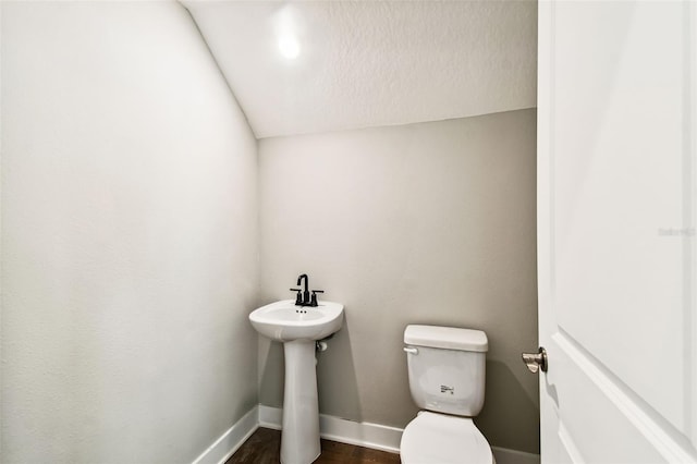 half bath with wood finished floors, toilet, and baseboards