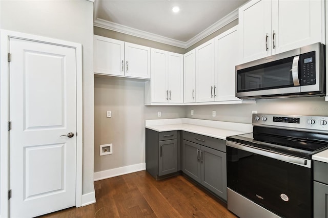 kitchen featuring ornamental molding, dark wood-style flooring, stainless steel appliances, light countertops, and gray cabinetry