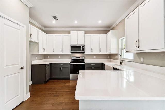 kitchen featuring stainless steel appliances, a sink, visible vents, dark wood-style floors, and crown molding