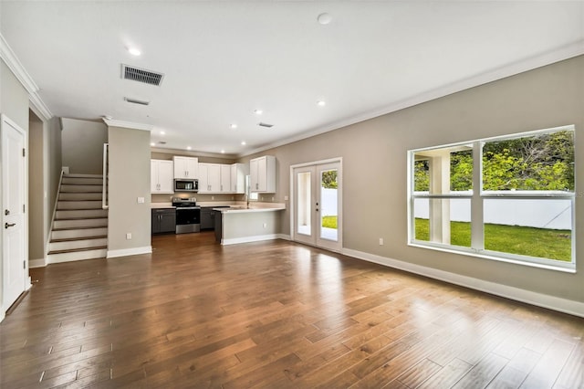 unfurnished living room featuring dark wood-type flooring, visible vents, french doors, stairway, and crown molding