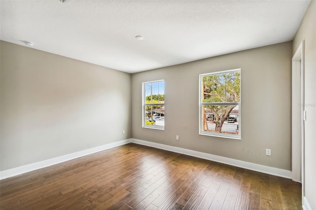 empty room featuring a textured ceiling and dark hardwood / wood-style floors