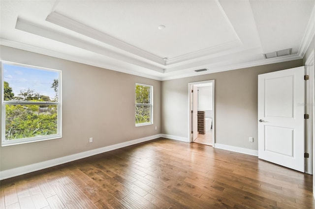 unfurnished bedroom with baseboards, visible vents, a tray ceiling, and wood finished floors