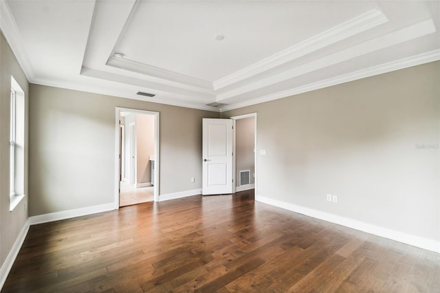 unfurnished bedroom featuring a tray ceiling, crown molding, and dark wood-type flooring