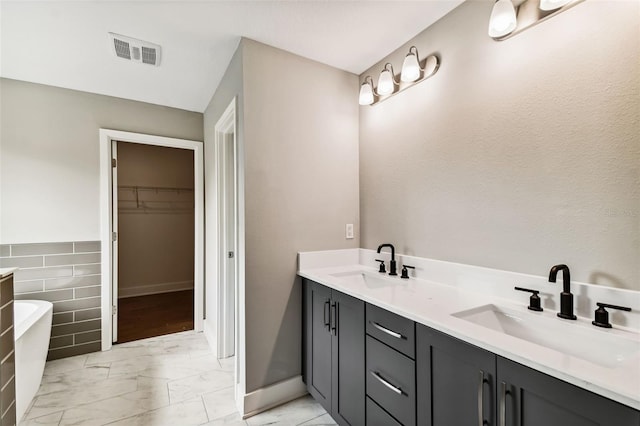 full bath with marble finish floor, visible vents, a sink, and a spacious closet