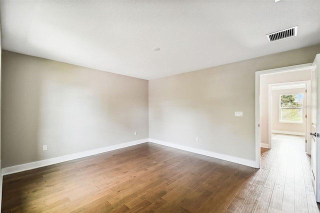 unfurnished room with baseboards, visible vents, and dark wood finished floors