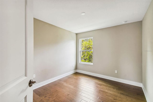 spare room featuring baseboards and wood finished floors