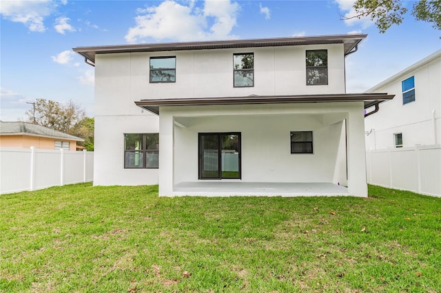 rear view of house with a yard, a patio area, fence, and stucco siding