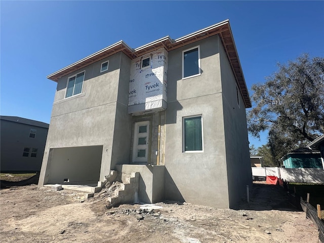 view of front of property featuring a garage, fence, and stucco siding