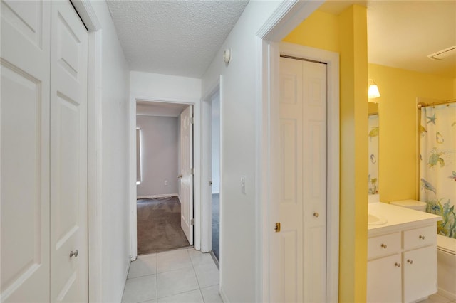 hall featuring a textured ceiling and light tile patterned floors