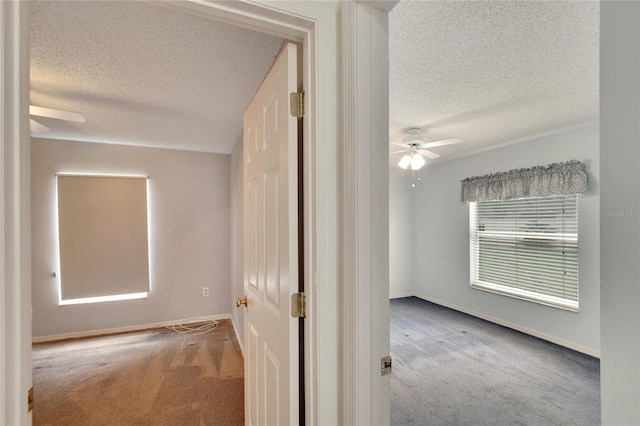 hall with a textured ceiling and carpet flooring