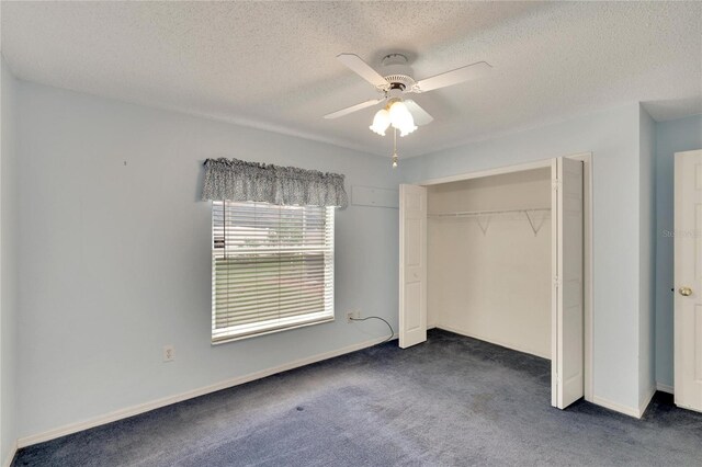 unfurnished bedroom with ceiling fan, a textured ceiling, a closet, and dark carpet