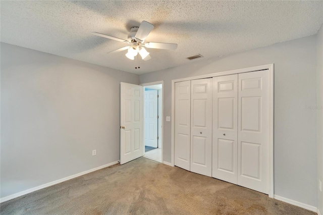 unfurnished bedroom with a textured ceiling, carpet, ceiling fan, and a closet